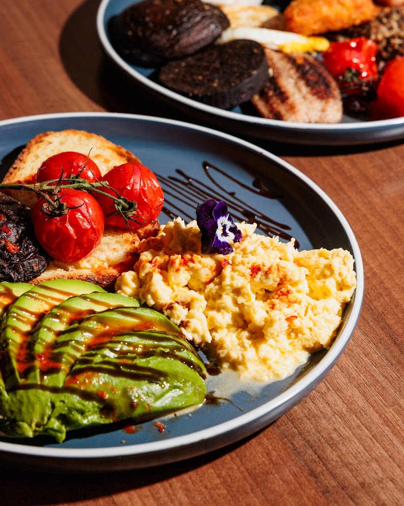 Scrambled eggs with avocado, vine tomatoes and toasted bread beautifully plated at Cafe Amara