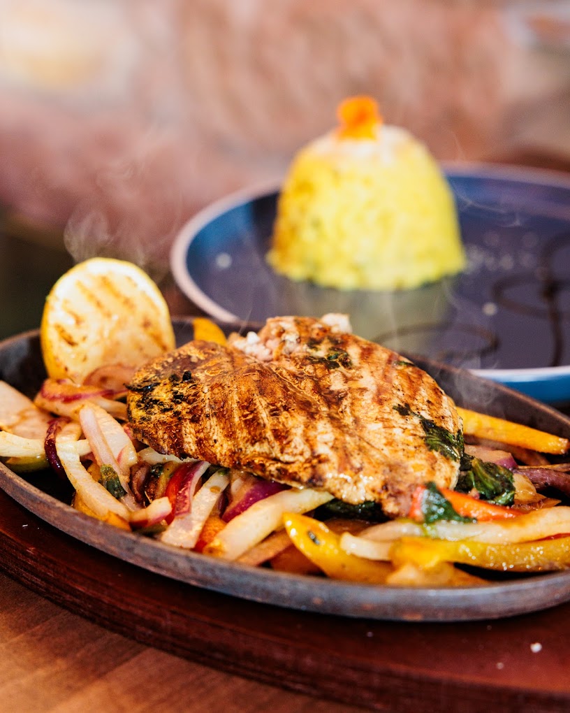 Sizzling cornfed chicken on a hot plate with peppers and onions at Cafe Amara